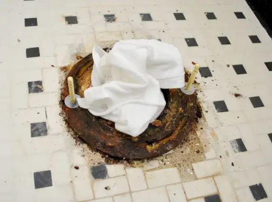 Nieuwe bouten op toiletflens met doek in rioolgat