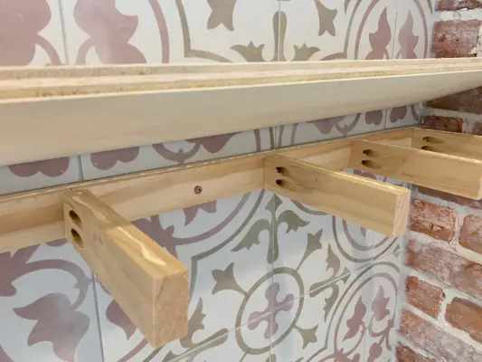 Multiplex blad wordt neergelaten op houten steunbeugel voor zwevende doe-het-zelf planken