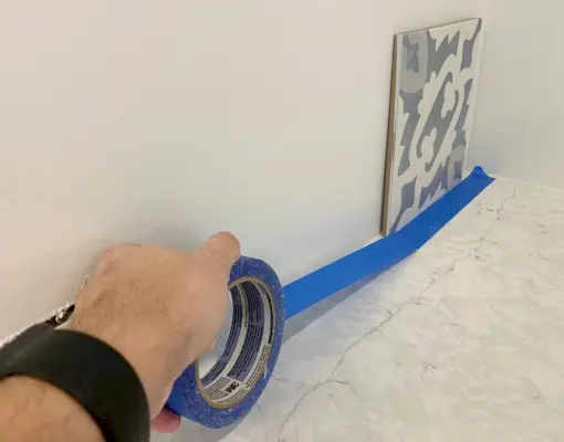 Het afplakken van de toonbank met blauwe schilderstape vóór installatie van de backsplash