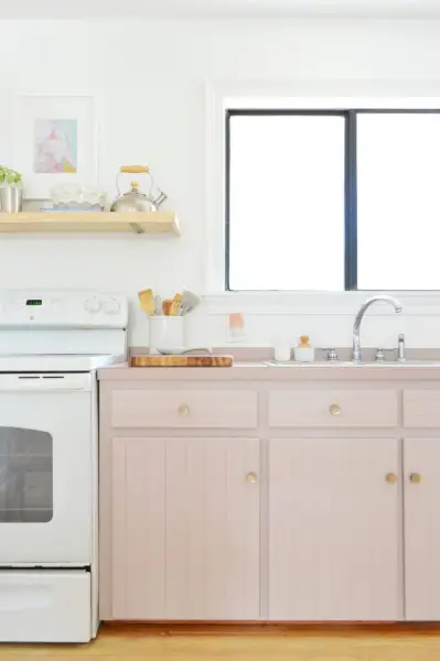 Oude kasten geschilderd in Artsy Pink met mauve laminaatbalies en witte kachel