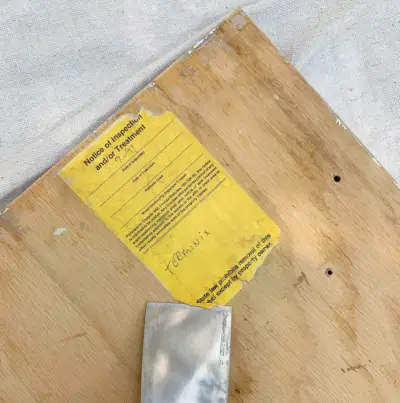 Het oude etiket van de achterkant van keukenkastjes schrapen als voorbereiding op het schilderen
