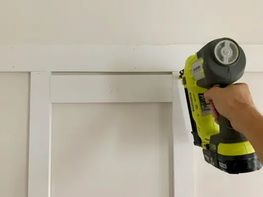 Verticale latten installeren met behulp van een spijkerpistool en een houten afstandsstuk