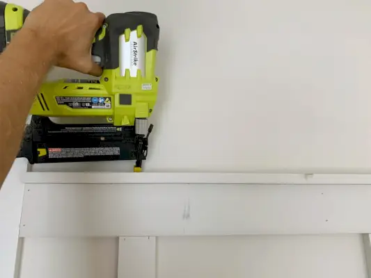 Spijkerpistool dat de bovenste raillip over de plank en de lat bevestigt
