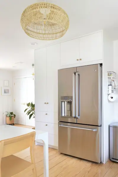 Witte Ikea keukenkastkasten tot aan het plafond, rond de koelkast gebouwd