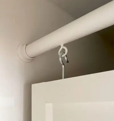 Ooghaak die het houten paneel ophangt aan de kaststang in de bijkeuken