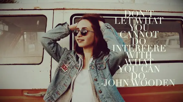 a girl in a denim jacket and sunglasses stands beside a red VW camper van