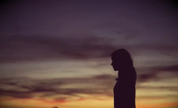 Silhouette of a woman looking at the horizon at sunset.
