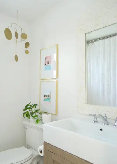 Witte badkamer met ingelegde spiegelgouden fotolijsten en messing mobiel