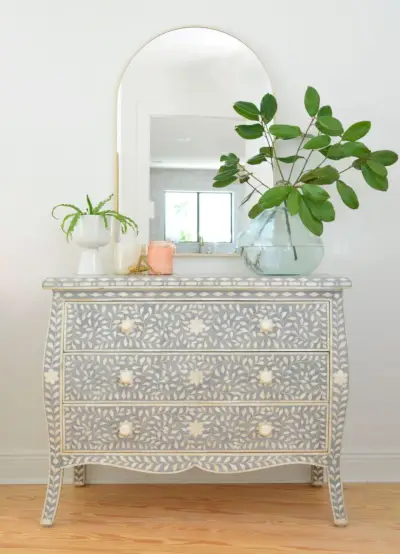 Blauw-wit ingelegd dressoir met koperen boogspiegel en grote plantenvaas