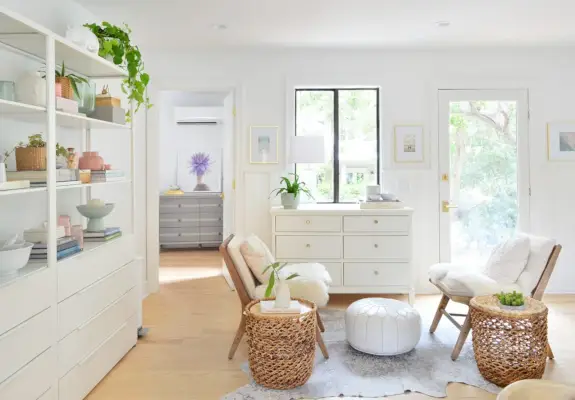 Strandachtige zitkamer met witte planken en grote dressoirs met zwevende stoelen en manden