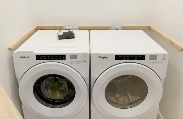 Houten wasplanksteunen toegevoegd aan de muren naast wasmachine en droger