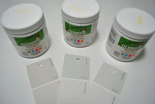 het testen van drie Benjamin Moore grijze verfopties gemengd in Olympische verftestblikken: Collingswood Grey Owl en Moonshine