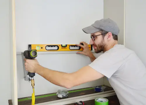 Man die waterpas gebruikt om planksteunstukken vast te spijkeren