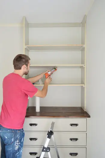 Man die onder de plank van een ingebouwde boekenplank breeuwt
