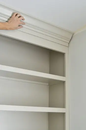 Hand die het kroonlijststuk op zijn plaats houdt op een doe-het-zelf-boekenplank