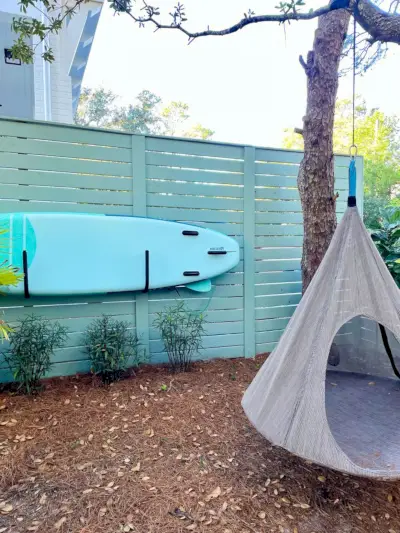 Zijtuin met paddleboard opgeslagen op hek met hangende tentschommel
