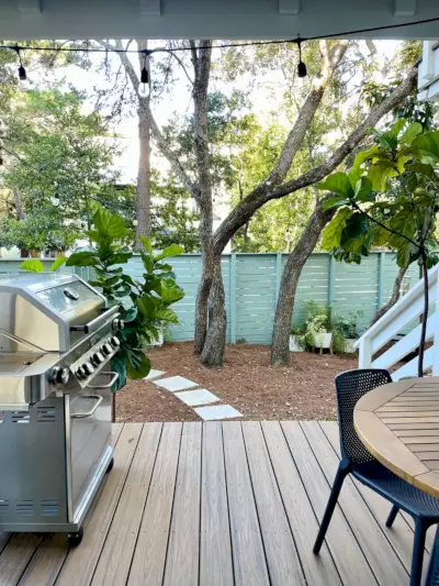 Verticaal zicht vanaf dekpatio met grill en tafel met uitzicht op groen in de tuin