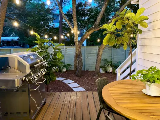 Uitzicht vanaf de keukenveranda met lichtslingers die gloeien boven de grill en een tafel om te eten