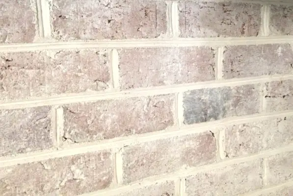 close-up detail van een open haard in een bakstenen muur waarop een doe-het-zelf-whitewash-behandeling is aangebracht