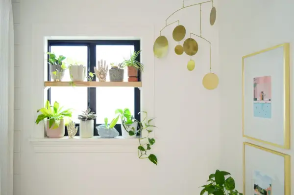 Houten raamplantenplank in de badkamer met gouden mobiel
