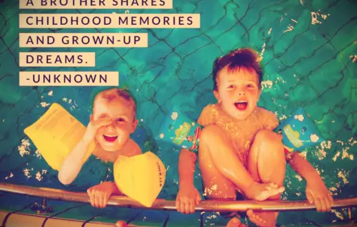 Two young brothers in Sesame Street floaties smiling up from inside a swimming pool