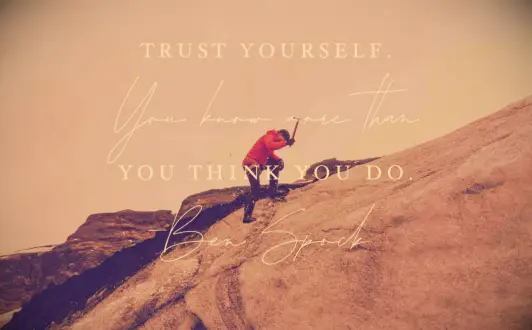 A mountain climber in a red parka scaling a granite rock face in Colorado