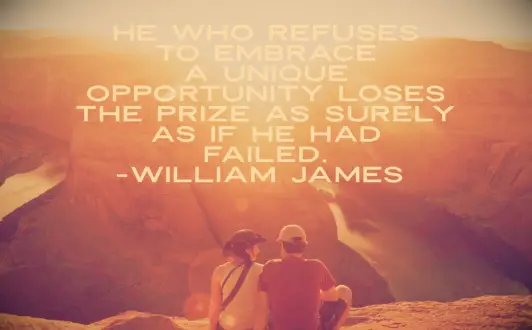 A couple sitting on a ledge overlooking a river in the Grand Canyon