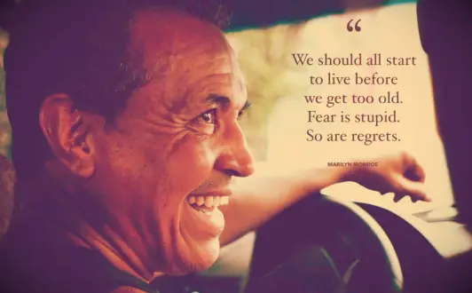 An old man smiling as he sits behind the wheel of a taxi in Rio De Janeiro