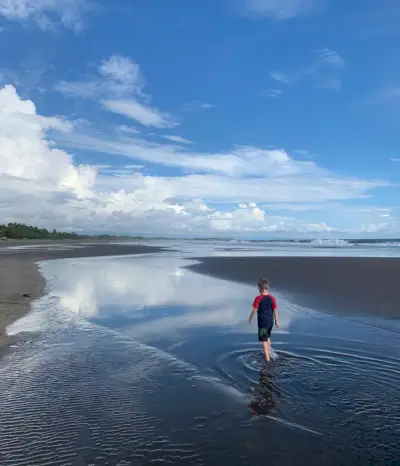 Jonge jongen speelt in de getijdenpool op het strand van Esterillos Oeste in Costa Rica