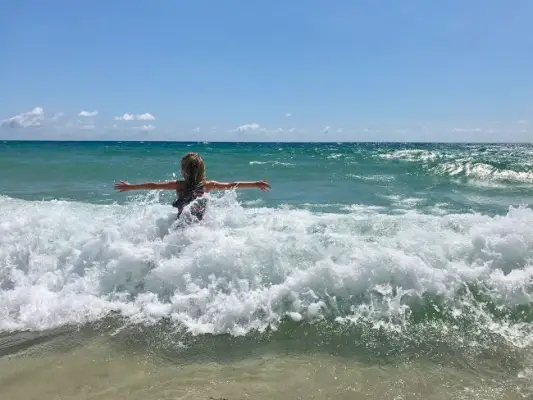 klein meisje speelt in golven tijdens de voorjaarsvakantie in Lauderdale By The Sea, Florida