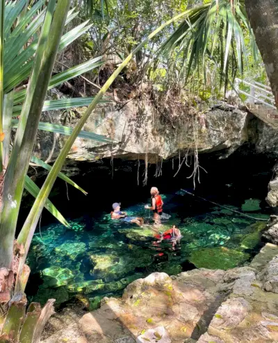 Familie zwemmen onder grot bij Cenote Cristalino in Akumal, Mexico