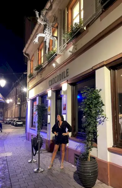 Kısa siyah elbiseli Sherry Crocodile restoranının önünde