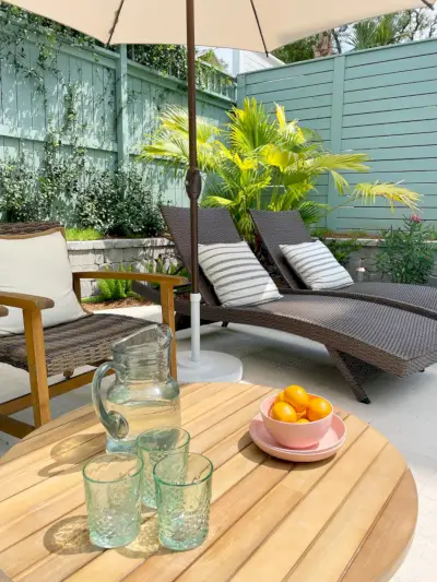 Zwembadpatio met bruine stoelen en rieten loungestoelen onder parasol