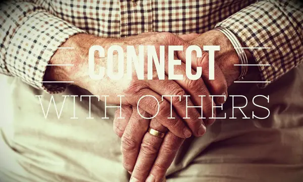 Two old hands clasped and balancing on the top of a cane