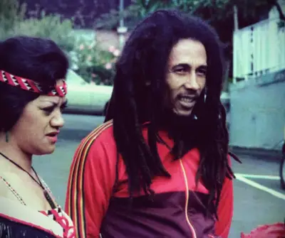 Bob Marley walking down the street with two women.