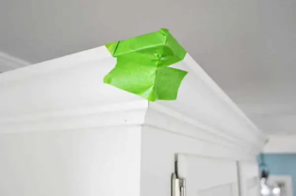 Groene schilderstape op de hoek van de keukenkroonlijst terwijl de lijm droogt