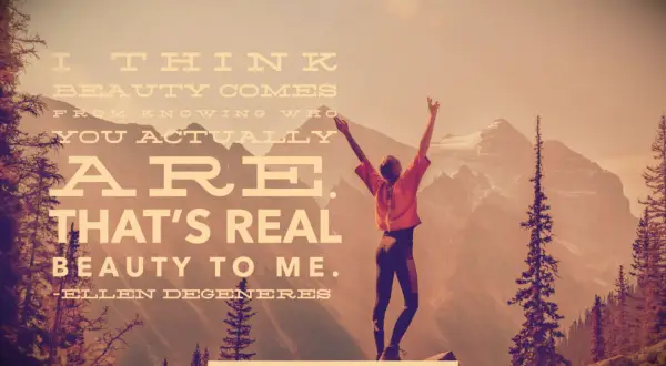 A woman on a maintain top raising her arms in the air