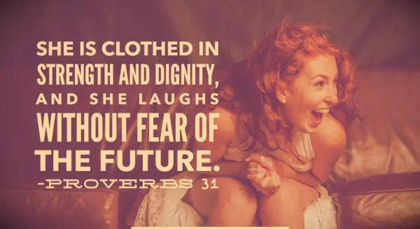 A redheaded woman on a couch smiling and laughing